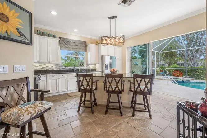 Kitchen featuring a center island, white cabinetry, decorative backsplash, stainless steel refrigerator with ice dispenser, and pendant lighting