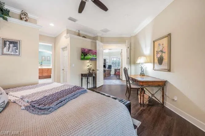 Bedroom with ceiling fan, dark wood-type flooring, ensuite bath, and crown molding