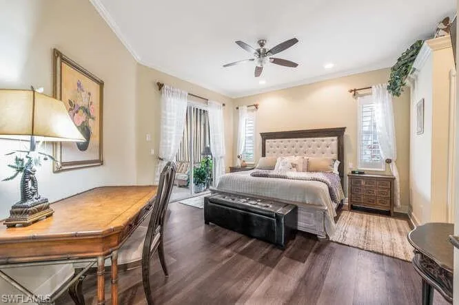 Bedroom featuring dark wood-type flooring, multiple windows, ceiling fan, and ornamental molding