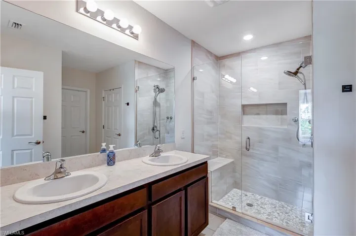 Full bath with double vanity, a shower stall, and tile patterned floors