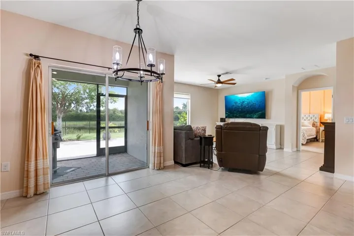 Living room with a chandelier, ceiling fan, light tile patterned flooring, and arched walkways