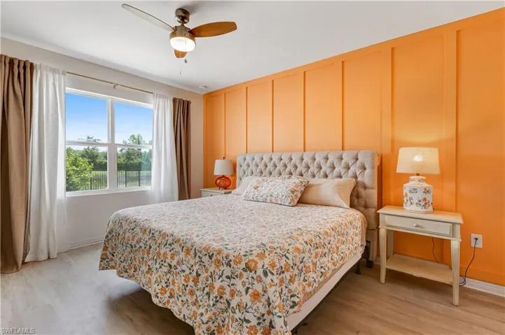 Bedroom featuring light wood-type flooring, a decorative wall, and ceiling fan