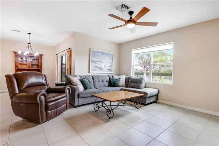 Living room with a chandelier, light tile patterned floors, and ceiling fan