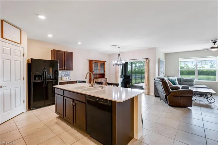 Kitchen featuring black appliances, light tile patterned floors, open floor plan, light countertops, and recessed lighting