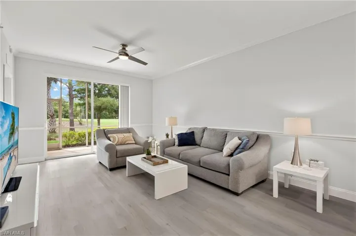 Living area with baseboards, light wood-type flooring, crown molding, and ceiling fan