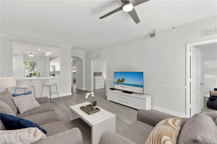Living area with crown molding, a ceiling fan, and arched walkways