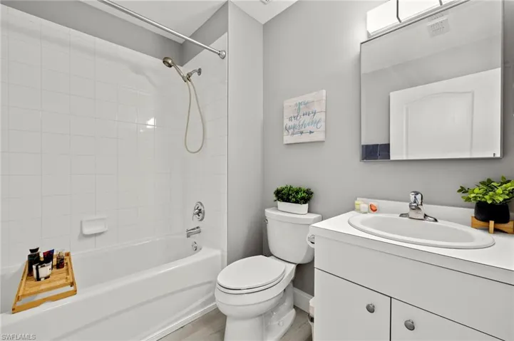 Full bath featuring baseboards, toilet, vanity, wood finished floors, and bathing tub / shower combination