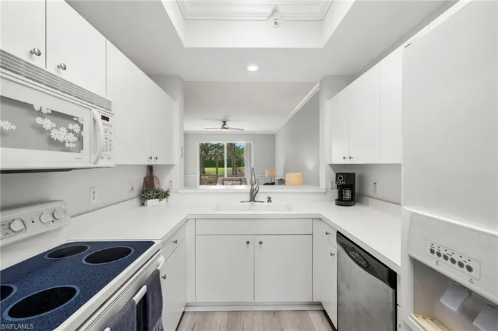 Kitchen featuring white appliances, white cabinetry, a sink, and crown molding