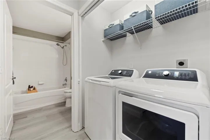 Laundry room featuring light wood-style flooring, laundry area, and washing machine and clothes dryer