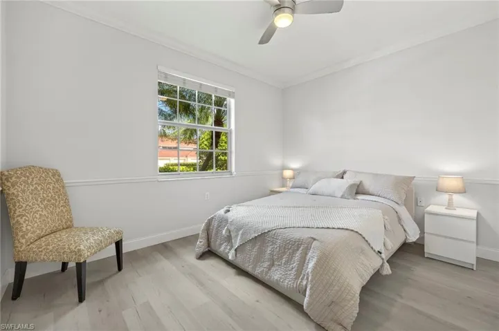 Bedroom with light wood finished floors, baseboards, crown molding, and a ceiling fan