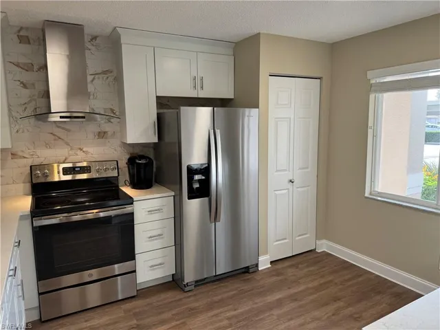 Kitchen featuring stainless steel appliances with stainless steel finishes, a textured ceiling, white cabinets, and dark hardwood / wood-style flooring