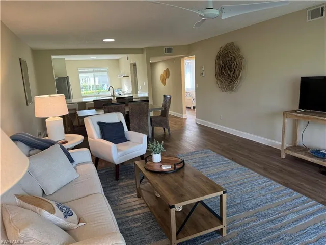 Living room featuring dark wood-type flooring, a textured ceiling, and ceiling fan