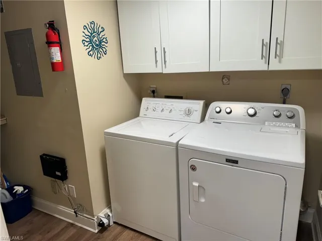 Laundry room featuring electric panel, cabinets, independent washer and dryer, and dark hardwood / wood-style floors
