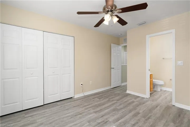 Unfurnished bedroom with light wood-type flooring, connected bathroom, a closet, and ceiling fan