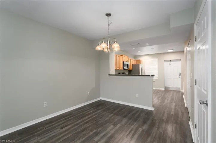 Empty room featuring a notable chandelier and dark hardwood / wood-style floors