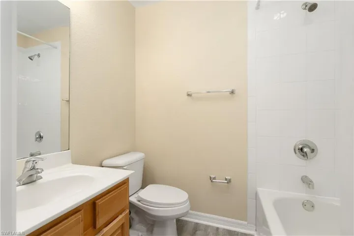 Full bathroom featuring vanity, wood-type flooring, tiled shower / bath combo, and toilet