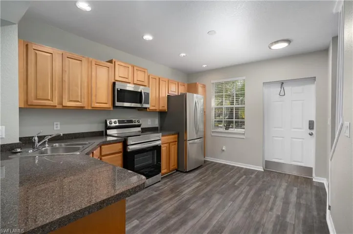 Kitchen with kitchen peninsula, sink, dark hardwood / wood-style floors, and appliances with stainless steel finishes