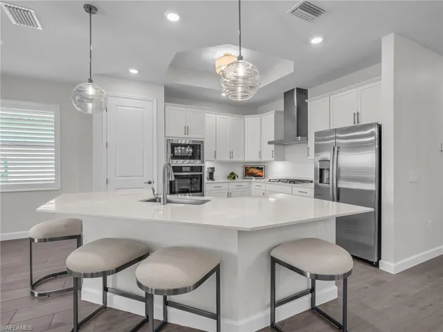 Kitchen featuring a large central island with seating, white cabinetry, stainless steel appliances, and recessed lighting