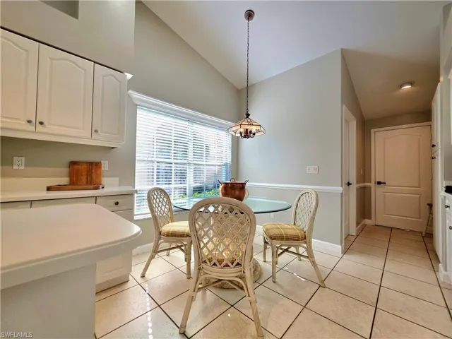 Kitchen featuring high vaulted ceiling, stainless steel gas stove, white cabinetry, a kitchen island, and light countertops
