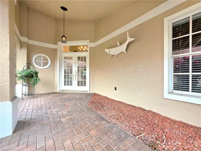 View of exterior entry featuring stucco siding, a sunroom, and french doors