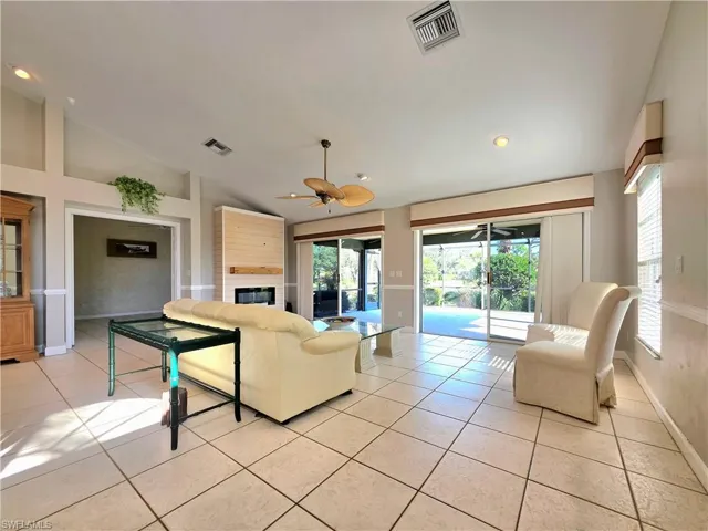 Kitchen with light tile patterned flooring, light countertops, freestanding refrigerator, a center island, and glass insert cabinets