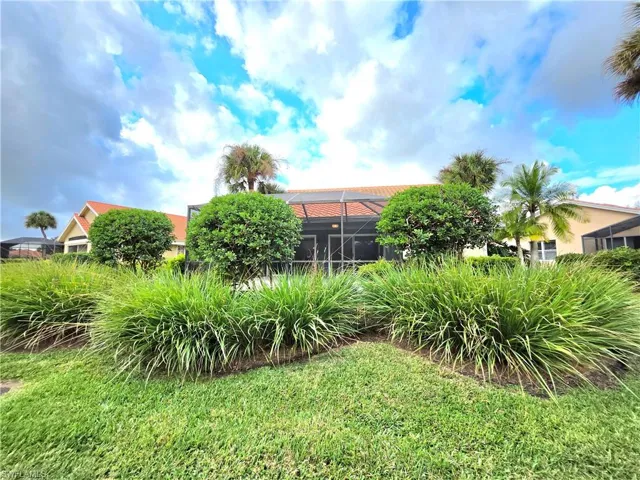 View of grassy yard featuring glass enclosure and a sunroom