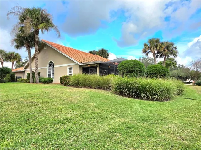 View of property exterior featuring a lawn, a lanai, stucco siding, and a tile roof