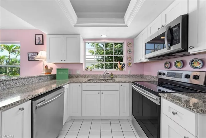 Kitchen with a sink, a healthy amount of sunlight, crown molding, and stainless steel appliances