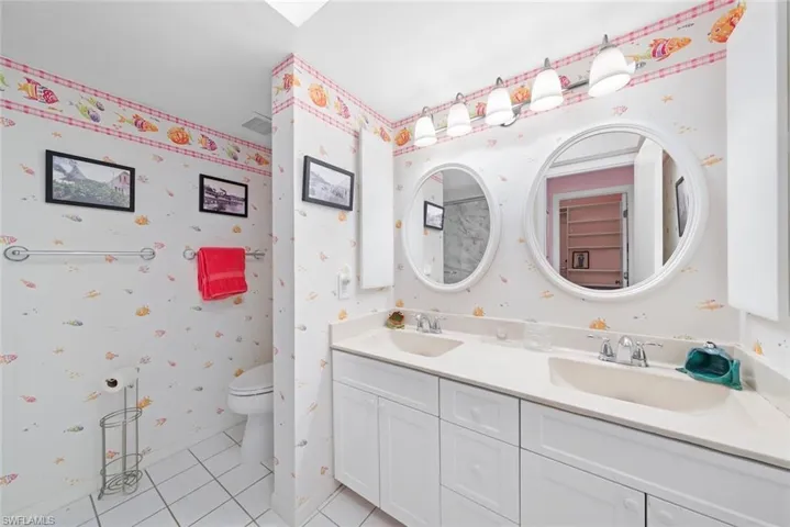 Full bathroom with wallpapered walls, tile patterned floors, a sink, and toilet