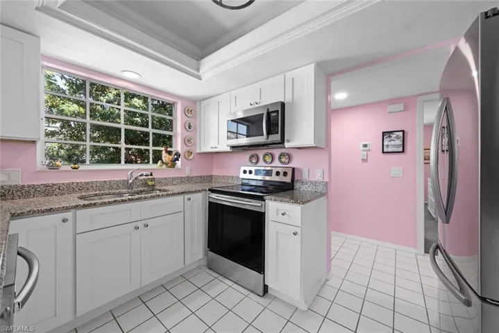 Kitchen with ornamental molding, white cabinets, recessed lighting, appliances with stainless steel finishes, and a sink