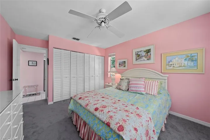 Carpeted bedroom featuring visible vents, baseboards, a ceiling fan, and a closet