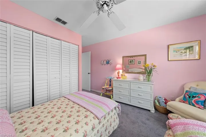 Bedroom featuring dark carpet, visible vents, ceiling fan, and a closet