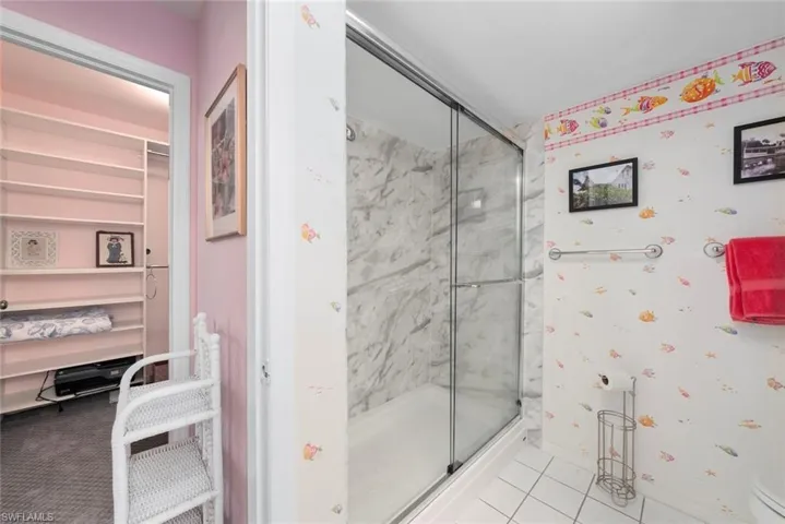 Bathroom with a shower stall, baseboards, tile patterned flooring, and toilet
