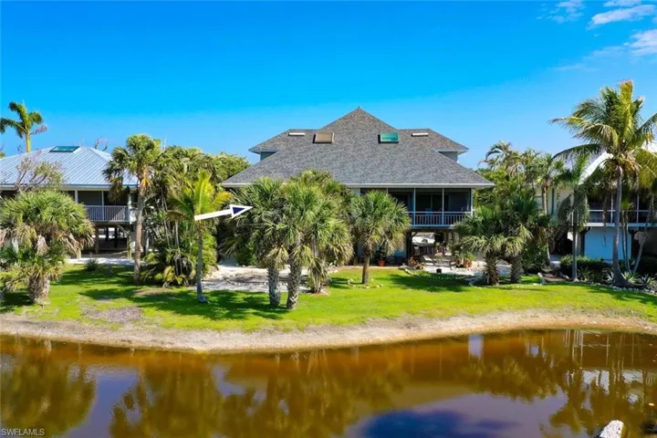 Rear view of property with roof with shingles, a lawn, and a water view