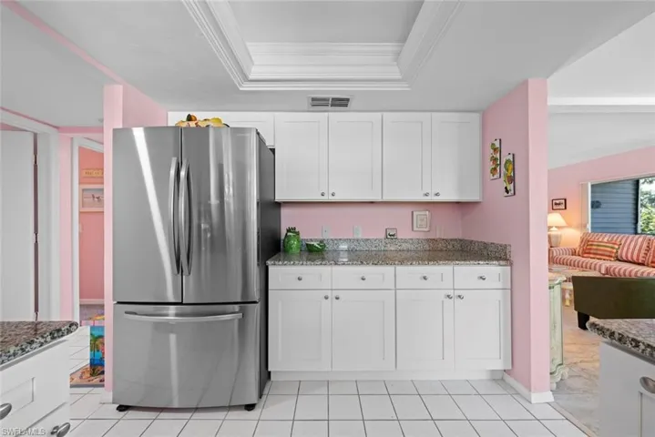 Kitchen featuring visible vents, freestanding refrigerator, and stone countertops