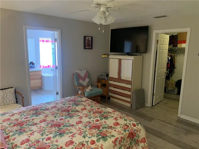 Bedroom with ceiling fan, ensuite bathroom, a walk in closet, hardwood / wood-style flooring, and a closet