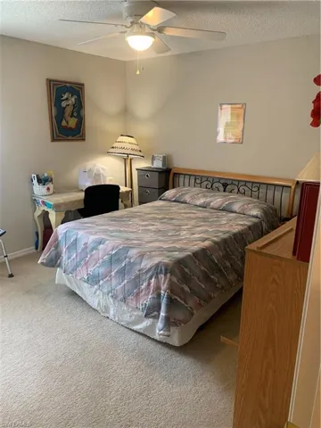 Carpeted bedroom featuring a textured ceiling and ceiling fan