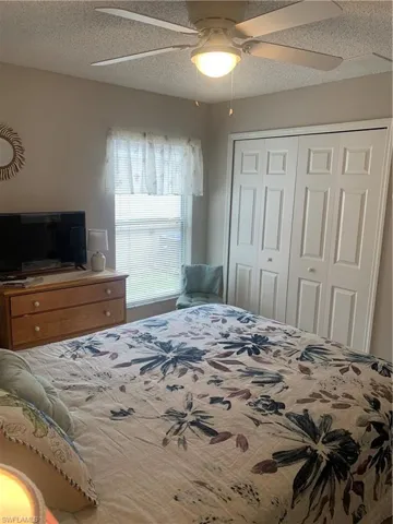 Bedroom with a textured ceiling, ceiling fan, and a closet