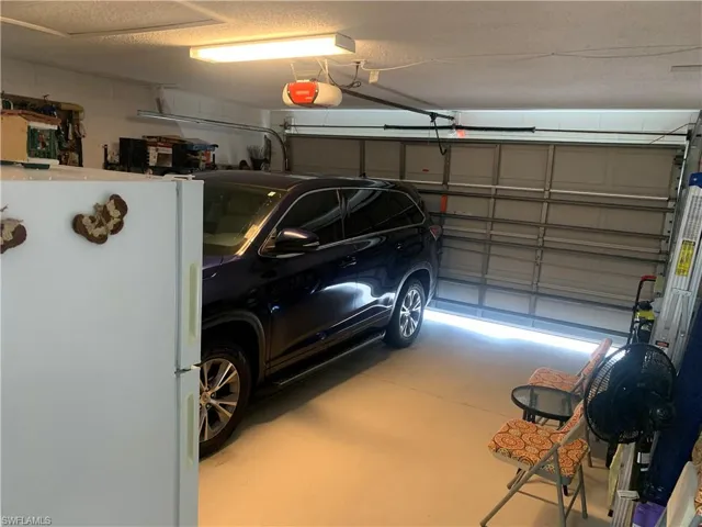 Garage featuring white refrigerator and a garage door opener
