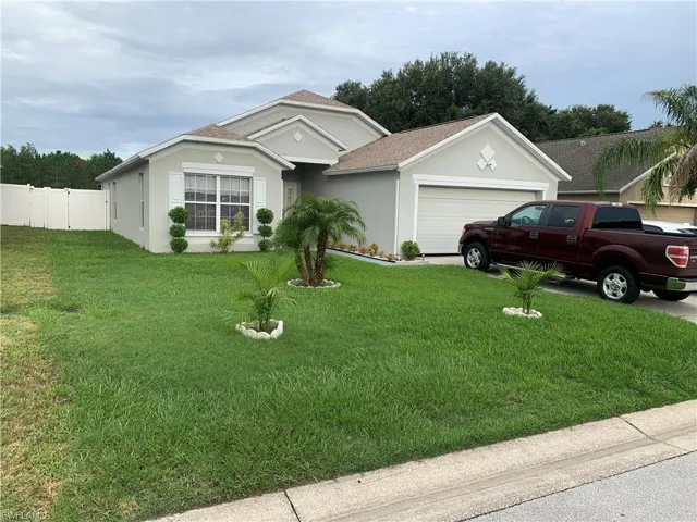 Single story home with a garage and a front lawn