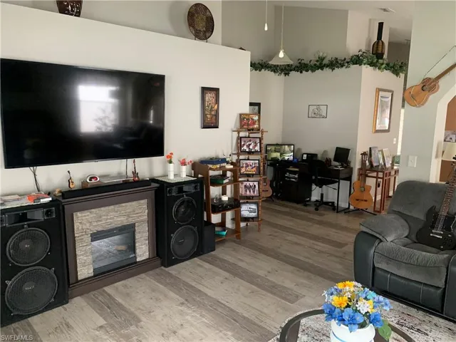 Living room with a stone fireplace, light wood-type flooring, and a towering ceiling
