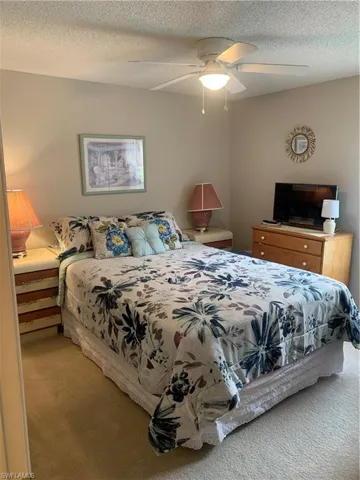 Carpeted bedroom featuring a textured ceiling and ceiling fan