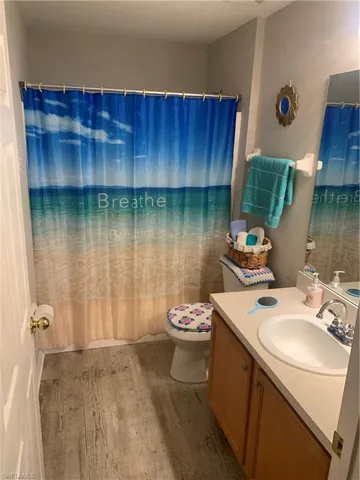 Bathroom featuring hardwood / wood-style flooring, toilet, and vanity