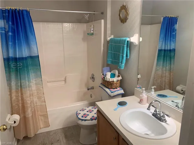 Full bathroom with vanity, toilet, hardwood / wood-style flooring, and shower / bath combination with curtain