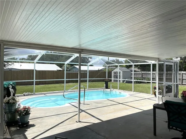 View of swimming pool featuring a lawn, a patio area, and a storage unit