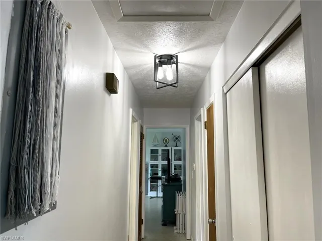 Corridor with a textured ceiling and carpet flooring