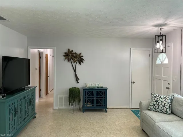 Living room with a notable chandelier and a textured ceiling
