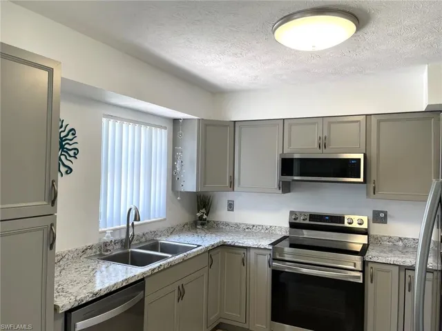Kitchen featuring sink, stainless steel appliances, a textured ceiling, and gray cabinets
