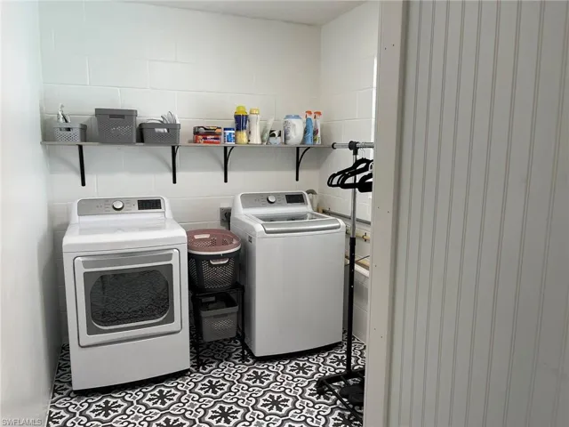 Laundry room featuring light tile patterned flooring and washing machine and dryer