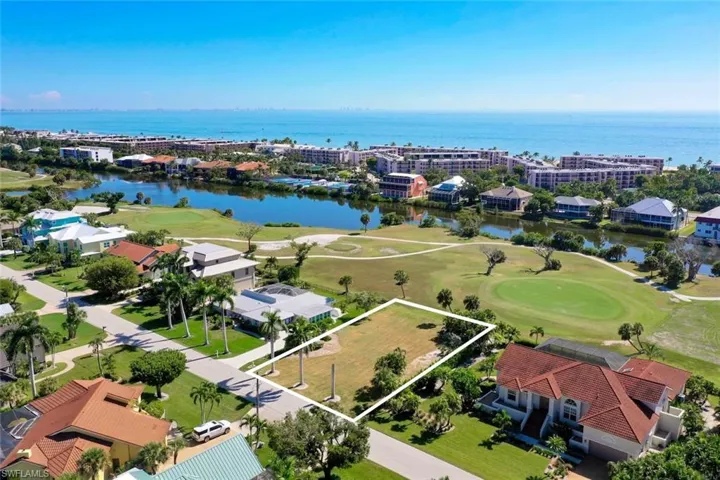 Aerial view of residential area with a golf club, property boundaries highlighted, and a nearby body of water
